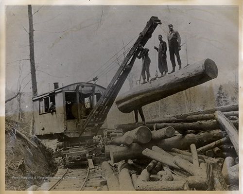 Three men standing on a log being raised by a machine