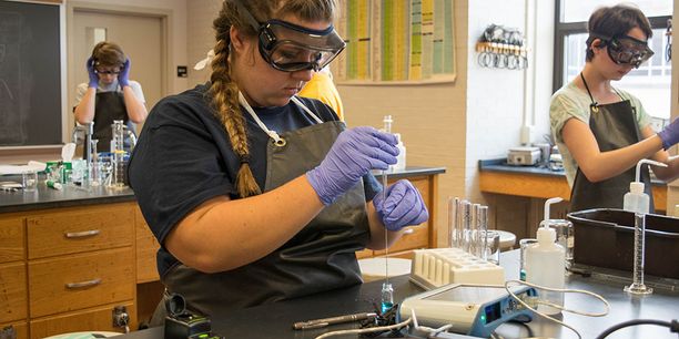 Person wearing goggles and gloves in lab