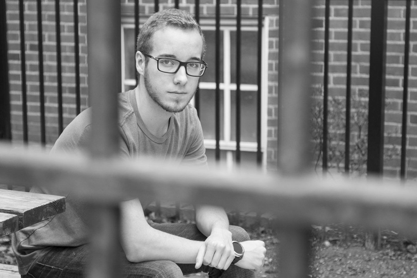 Man wearing glasses with prison gates in front and behind him