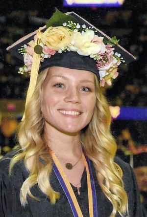 Woman wearing commencement regalia with flowers on her cap